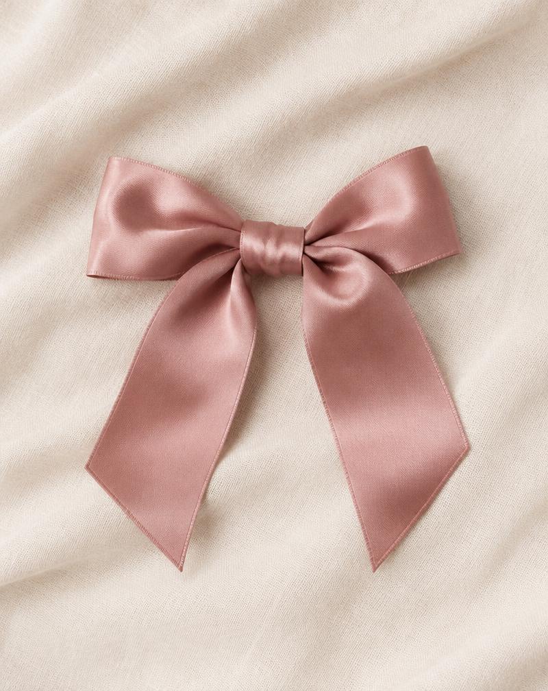 Pita satin berwarna dusty rose di atas kain linen krem