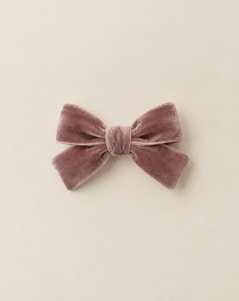 Pita velvet kecil berwarna mauve di atas kertas krem